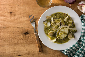 Hake fish and clams with green sauce on wooden table. Typical spanish recipe.	