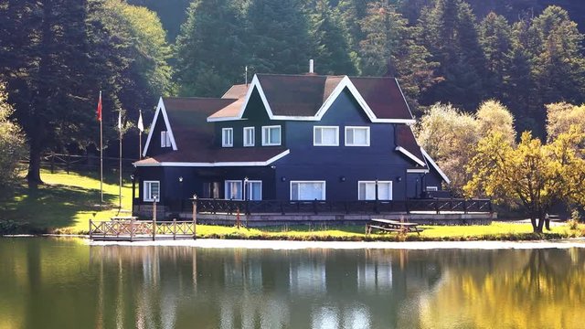 Yellow foliage and mirror surface of the lake, reflection of Autumn. Zoom out. Vacation cottage by the lake at Golcuk, Bolu in Turkey. Calm water reflects the scene and landscape