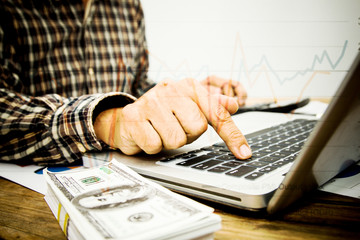 businessman hands searching for data on Notebook with analyzing charts at his workplace.