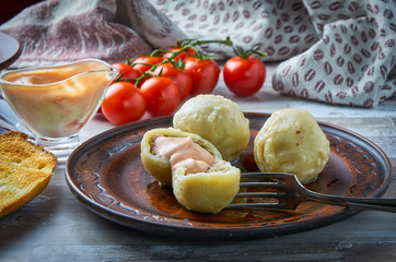 Khinkali is a national Georgian dish. On a clay plate with a sauceboat and cherry tomatoes in the background. Close-up. Horizontal.