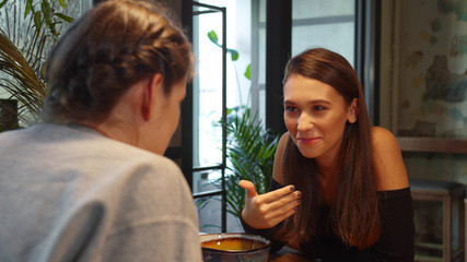 Two girls at lunch, they sit and talk to each other friendly