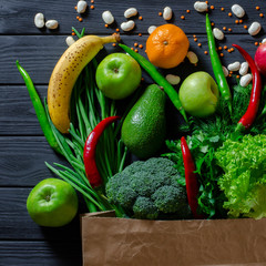 Top view paper bag of different fresh health food on white wooden background