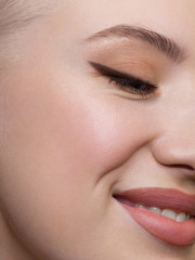 Fototapeta premium Half a beauty portrait with beautiful fashionable day make-up, black liner on eyes and extremely long eyelashes. natural lipstick on the sexy lips. Cosmetology and spa facial skin care