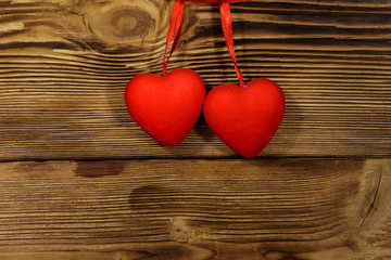 Two red hearts hanging over wooden background