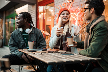 Pretty smiling girl waving hand to male friend outdoors
