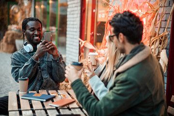 Happy Afro American man holding mobile phone in cafe