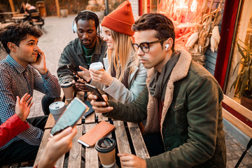 Young friends sitting in street cafe and spending time together