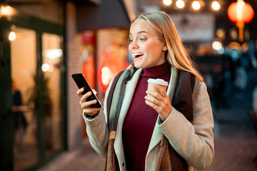 Joyful pretty lady reading messages on the phone outdoors
