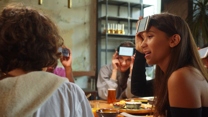 Group of friends sit in a cafe, play in word game with phones