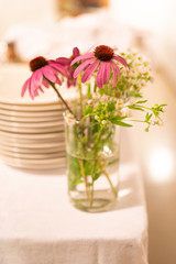 wedding centerpiece with bouquet of flowers and a couple of pink echinacea  in glass vase on table