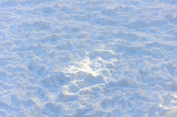 White snow on the playground with traces of numerous legs after the children's winter games. Blue snow with a bright sunny spot in the center. Background. Pattern. Concept.