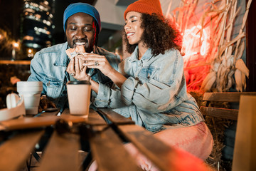 Happy Afro American enjoying food in street cafe