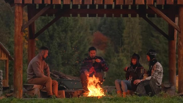 Group of people near big campfire relaxing and drink coffee or tea 4K 