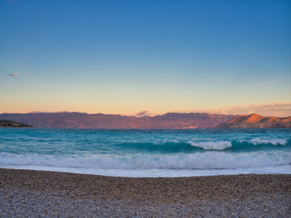 Fototapeta na wymiar Sunset over spectacular blue sea and with illuminated mountain on the horizon