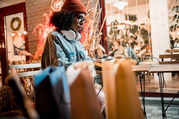 Young attractive lady sitting and using smartphone outdoors