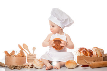 Little cook with a bagel in her hands. Obesity and hunger concept. Gaining weight. Diet. Turkish pretzel with sesame