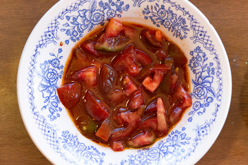 Juicy tomato salad in a white plate with a blue pattern, close-up