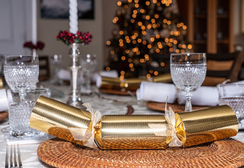 Traditional british christmas lunch table setting with crackers and glasses with xmas tree in the...