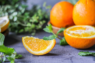 Photo of fresh orange on retro background. A slice of orange with green leaves. Half of orange on wooden plate bowl. Free space for text. Dark background. Image