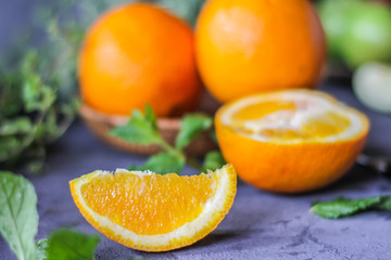 Photo of fresh orange on retro background. A slice of orange with green leaves. Half of orange on wooden plate bowl. Free space for text. Dark background. Image