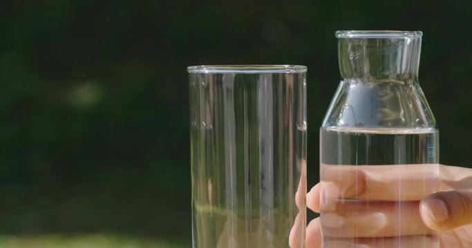 Slow motion of human hand pick up the bottle and pouring pure water in to the glass make the spread of water crystal bubble