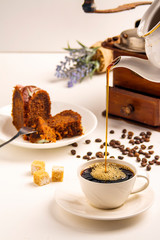 Exposition of chocolate cake with cup a coffee, coffee grinder on background. White background