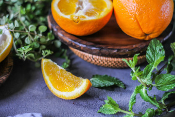 Photo of fresh orange on retro background. A slice of orange with green leaves. Half of orange on wooden plate bowl. Free space for text. Dark background. Image