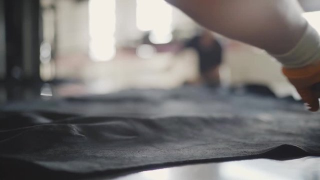 Workers are preparing leather, making it maximum flat before ironing process 