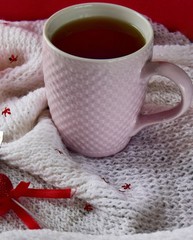 Obraz na płótnie Canvas one Cup of tea on a white scarf with a tangerine heart.soft focus