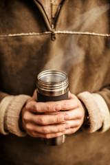 Cup of hot drink is holding by hands 