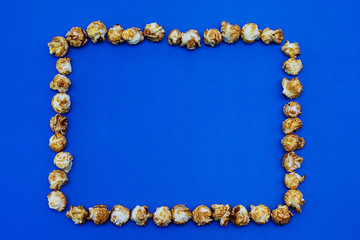 Frame of caramel popcorn on a blue background. The concept of the film. Food for watching movies. View from above. 2020 blue color background