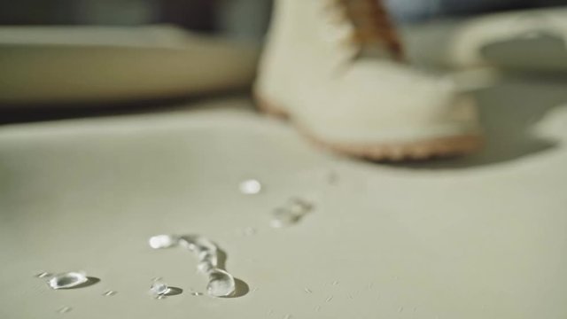 Water falling on the boot made of  waterproof leather materials. Drops of water flow down the leather surface