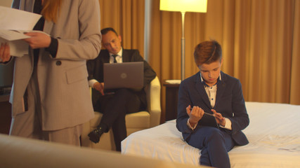 Man in work on laptop, little boy sit with tablet,woman look on documents in hand