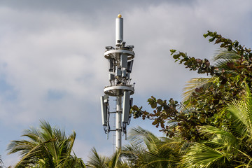 Gray metal cell tower carrying antennas of cellular networks on the blue sky with white clouds...