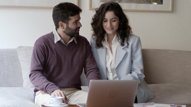 Happy woman and man having video call through laptop. Smiling young couple talking with interlocutor through laptop. Communication and technology concept