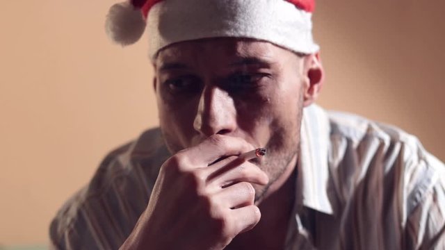 Depressed Santa, Young man with Santa Claus hat smoking cigarette caused by New Year or Christmas holidays depression and loneliness