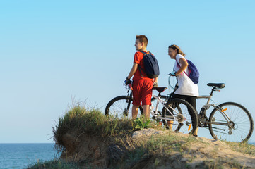 Obraz premium boy and young woman on a Bicycle on a cliff by the sea