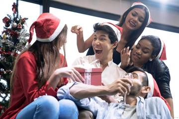 Group of friends laughing and sharing Christmas gifts.