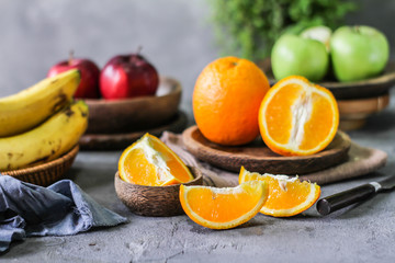 Photo of fresh orange on retro background. Slice of orange in front of fruits and vegetables. Half of the orange on wooden plate bowl. Sunkist. Summer. Image