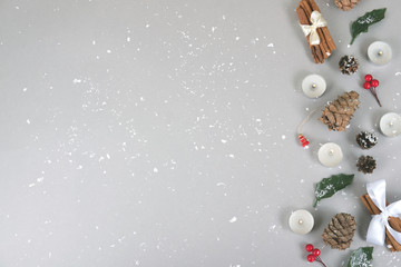 Small candles, forest pinecones, red berries and green leaves with festive cinnamon sticks in snow.