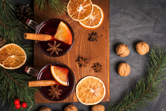 Red spicy Christmas mulled wine in two glasses with orange slices on the basis of red wine with spicy cinnamon sticks, star anise, on a black background. The view from the top.