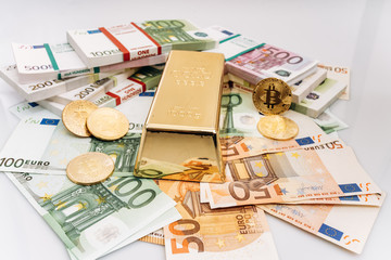 Bitcoin BTC Gold coins with bills of euro banknotes and gold bullion. Bitcoin and gold lie on Euro banknotes