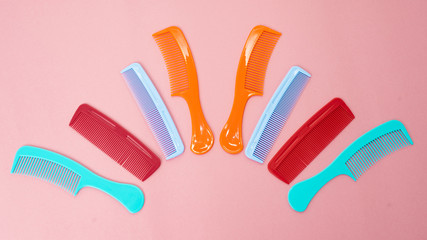 Various colored brushs and combs for hair on pink background. collection of combs