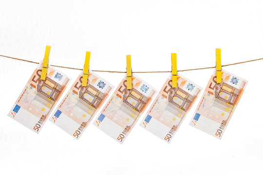 Euro banknotes are attached with yellow clothespins to a rope on a white background
