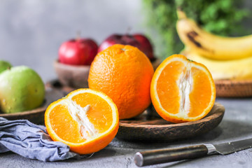 Photo of fresh orange on retro background. Slice of orange in front of fruits and vegetables. Half of the orange on wooden plate bowl. Sunkist. Summer. Image