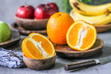 Obraz na płótnie Canvas Photo of fresh orange on retro background. Slice of orange in front of fruits and vegetables. Half of the orange on wooden plate bowl. Sunkist. Summer. Image