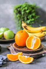 Photo of fresh orange on retro background. Slice of orange in front of fruits and vegetables. Half of the orange on wooden plate bowl. Sunkist. Summer. Image