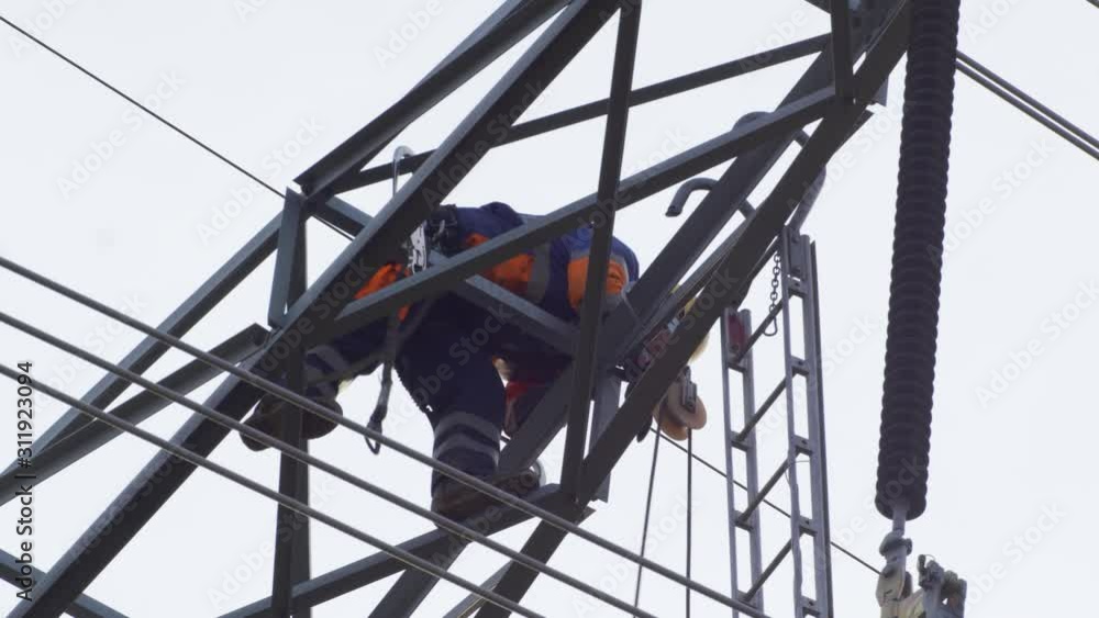 Poster worker working high up on electrical power lines. camera angled up.