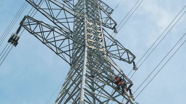 Electric engineer works high up on a high voltage pole.