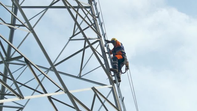 Electrician climbs up pylon, secured with a rope. 